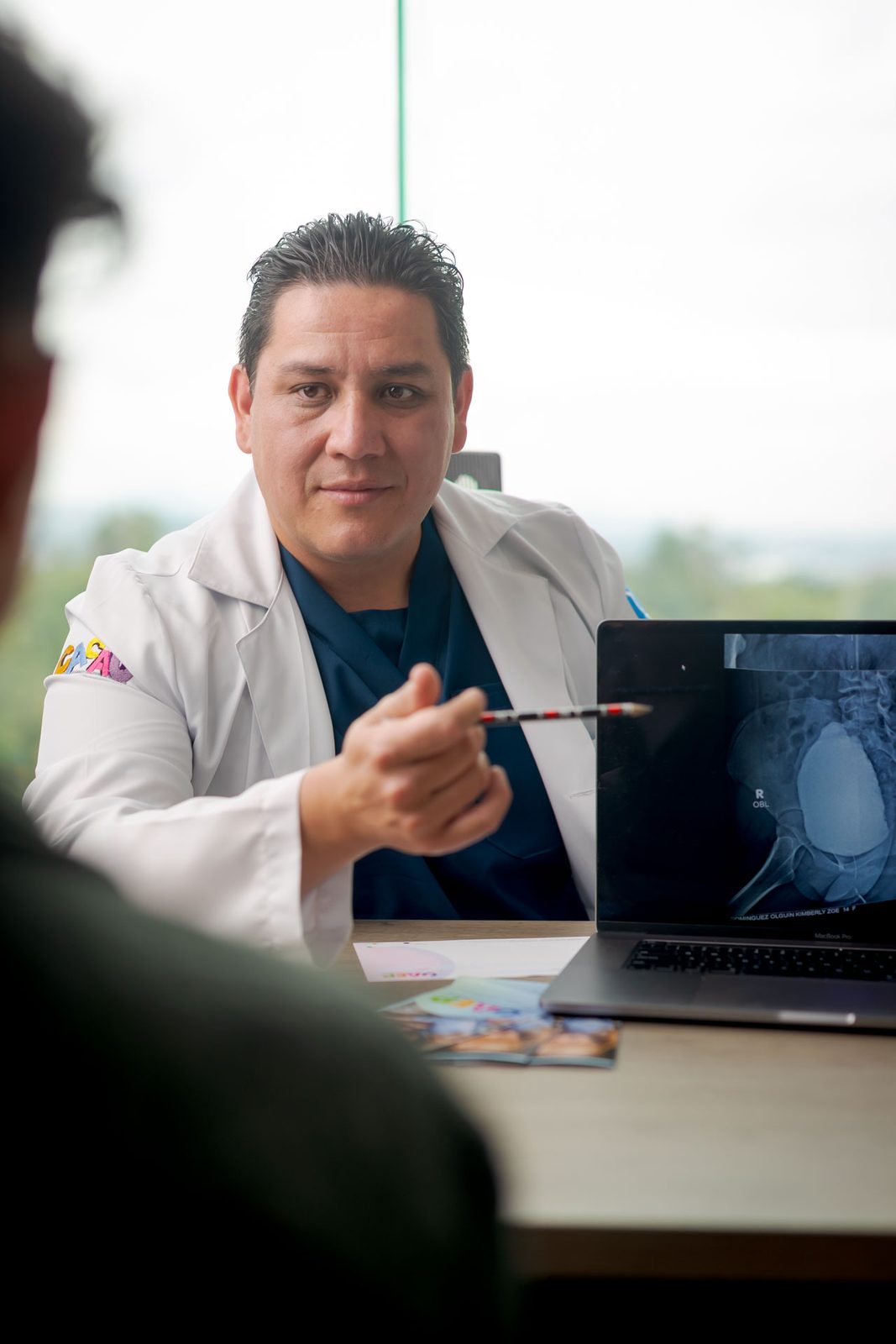 El Dr. Rafael Jordan explica un estudio a un padre de familia en consulta