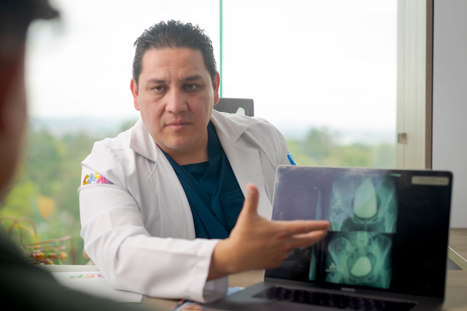 El Dr. Rafael Jordan explica un estudio de imagen a un padre de familia durante la consulta